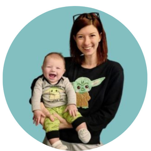 women in a black sweater with baby yoda on it, holding a baby boy smiling wearing baby yoda pajamas