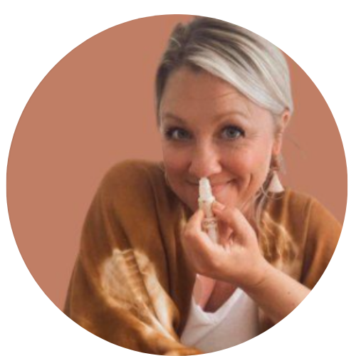 Blonde woman smirking at the camera wearing a brown sweater