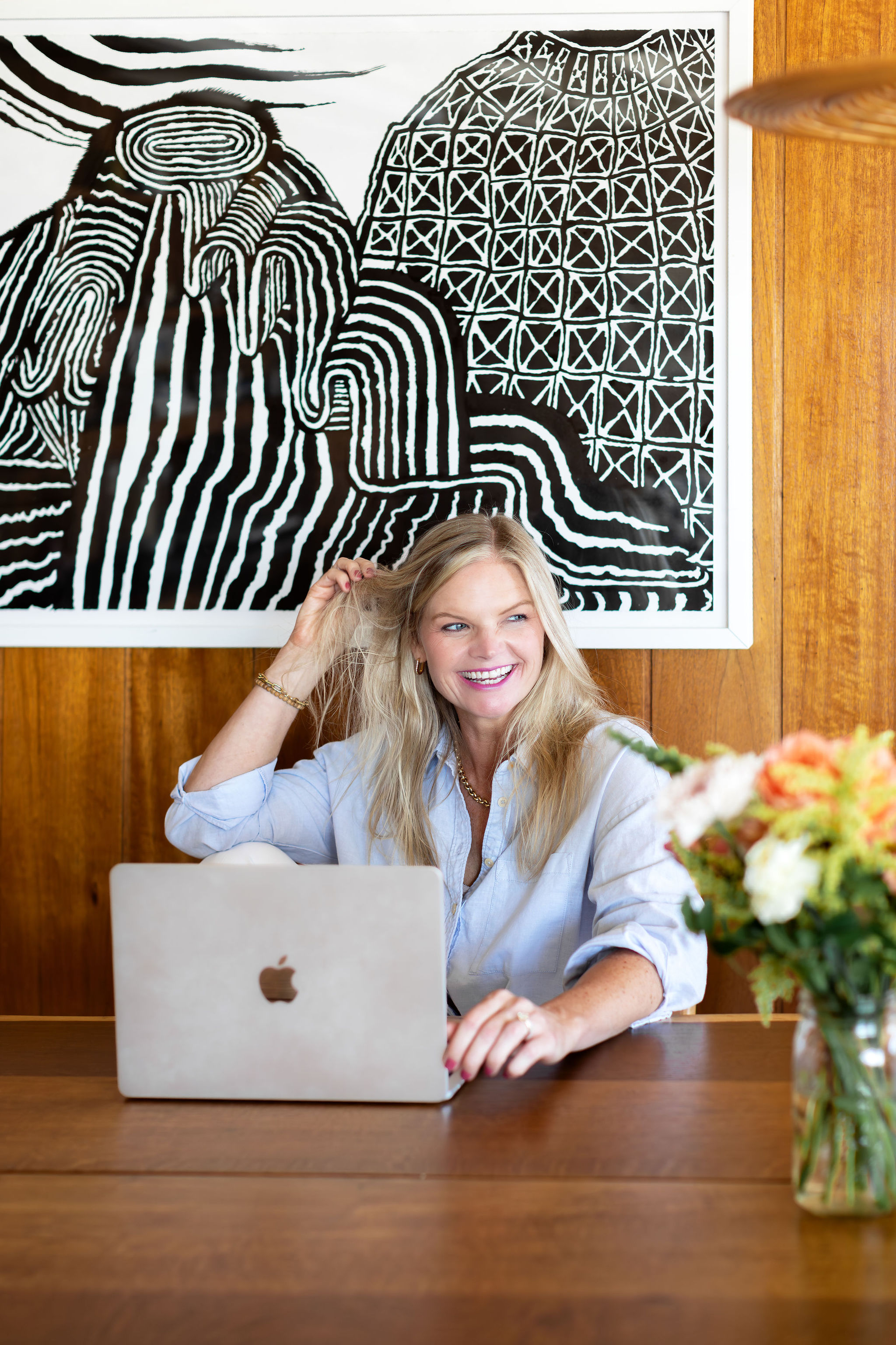 Em wearing a grey shirt sitting on a couch smiling at the camera