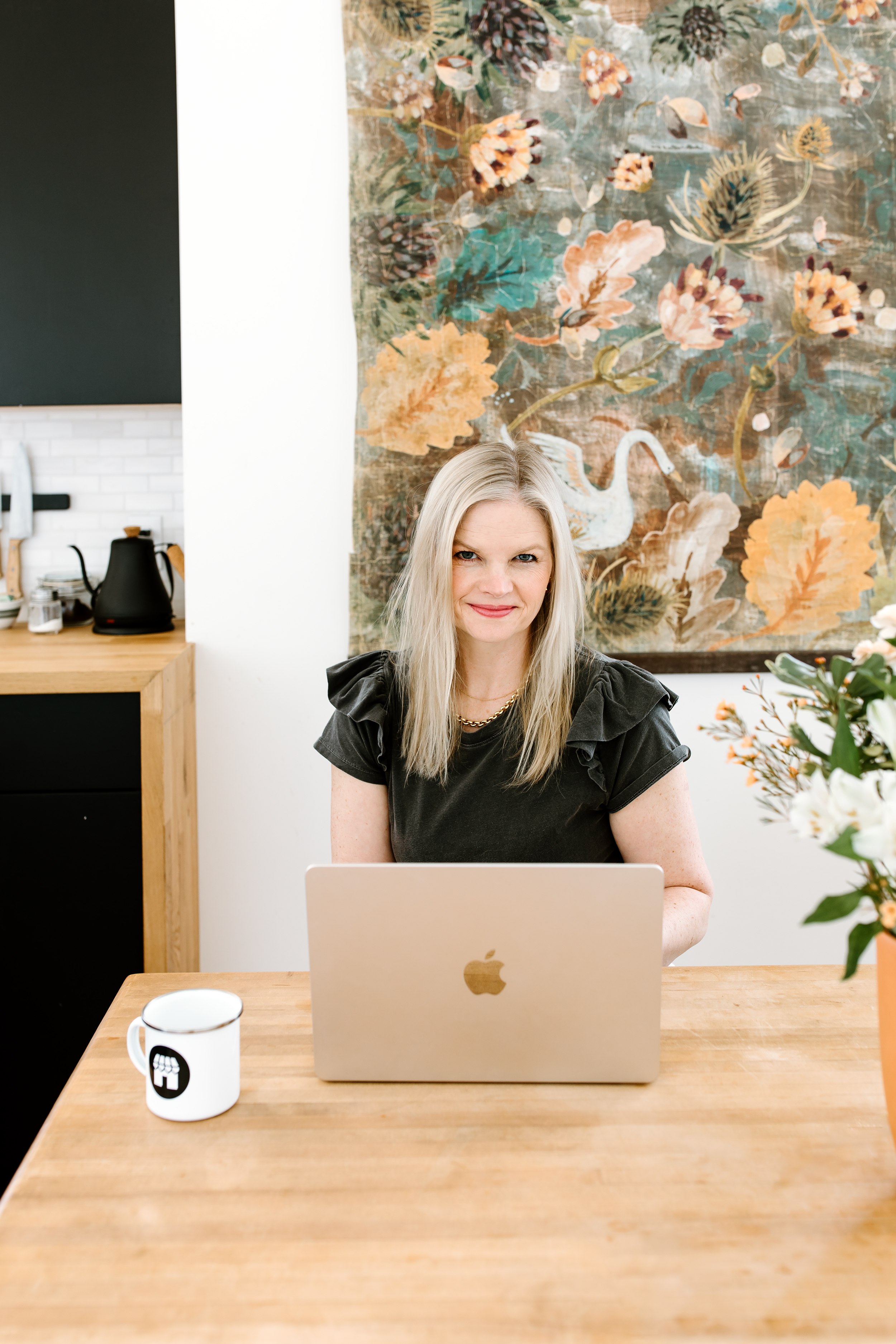 Em in a grey shirt sitting behind her laptop with her coffee mug next to her