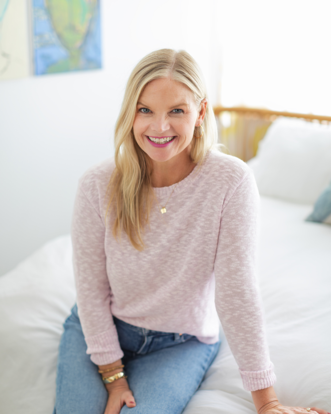 Em wearing a grey shirt sitting on a couch smiling at the camera