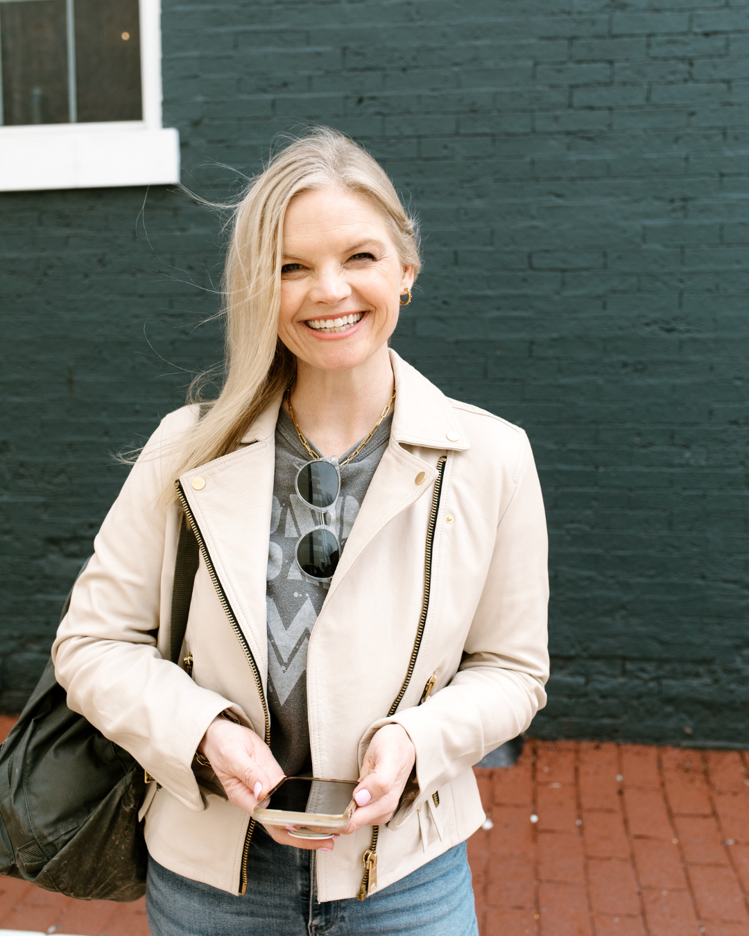 Em holding her phone, standing outside smiling