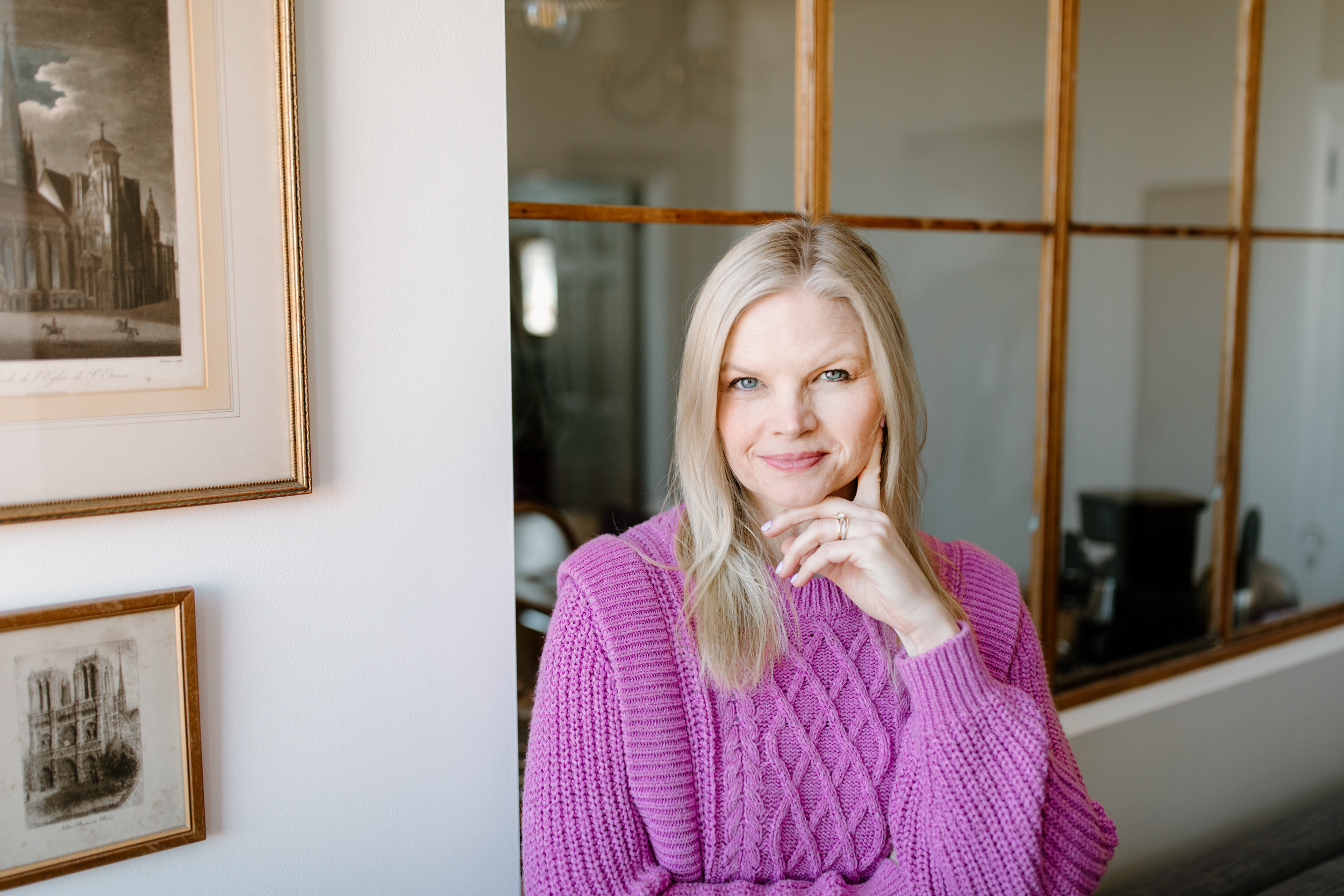Em wearing a pink sweater with her hair down, looking at the camera and smiling